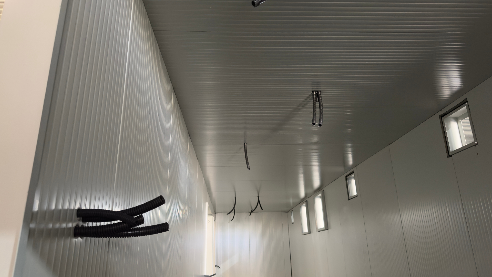 FlexEskid interior under fit-out — insulated wall and ceiling panels with pre-routed cable conduits and recessed LED lighting ready for equipment installation.