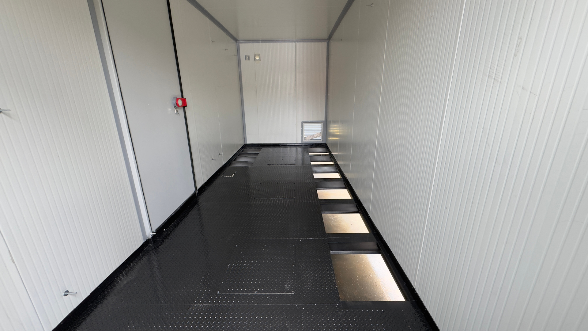 FlexEskid raised steel floor — chequer-plate panels on a structural support frame with cable access cut-outs for under-floor routing.