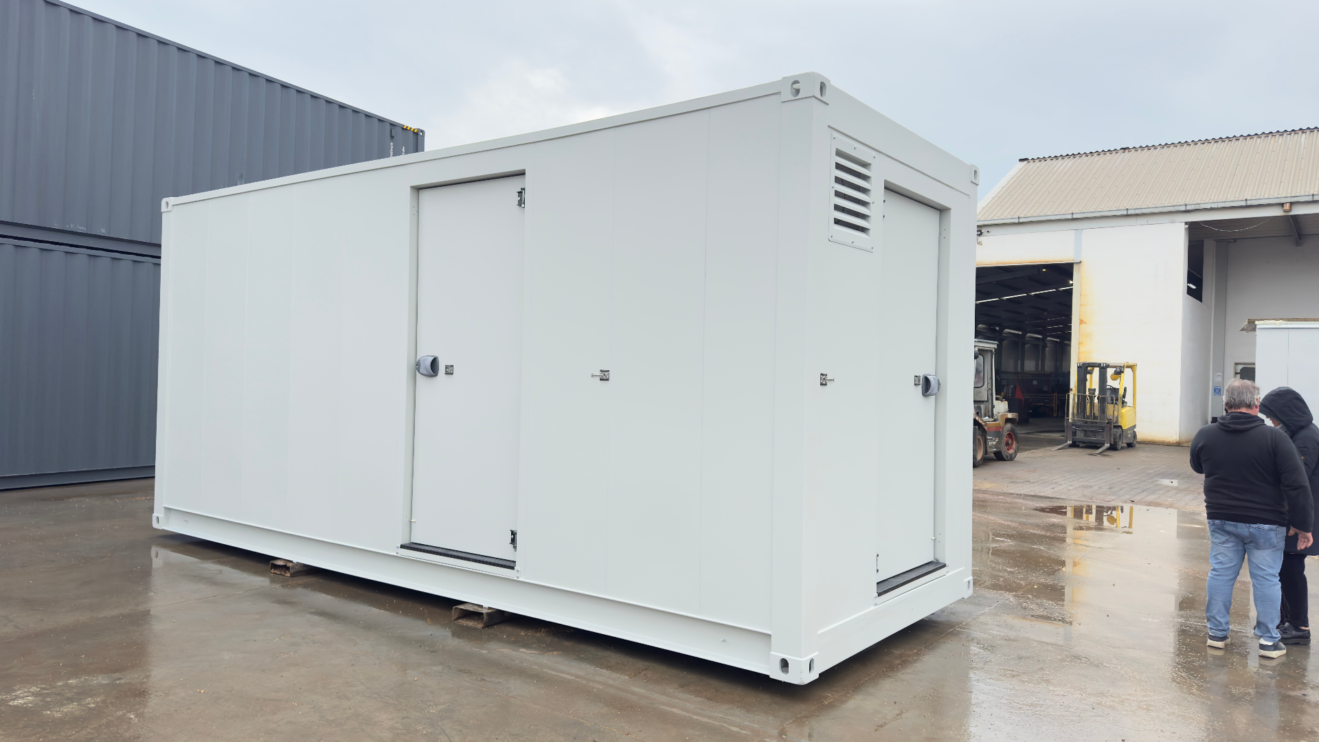 FlexEskid exterior — factory-finished white acoustic enclosure with personnel access door, side ventilation louvre and ISO corner castings for craning and transport.