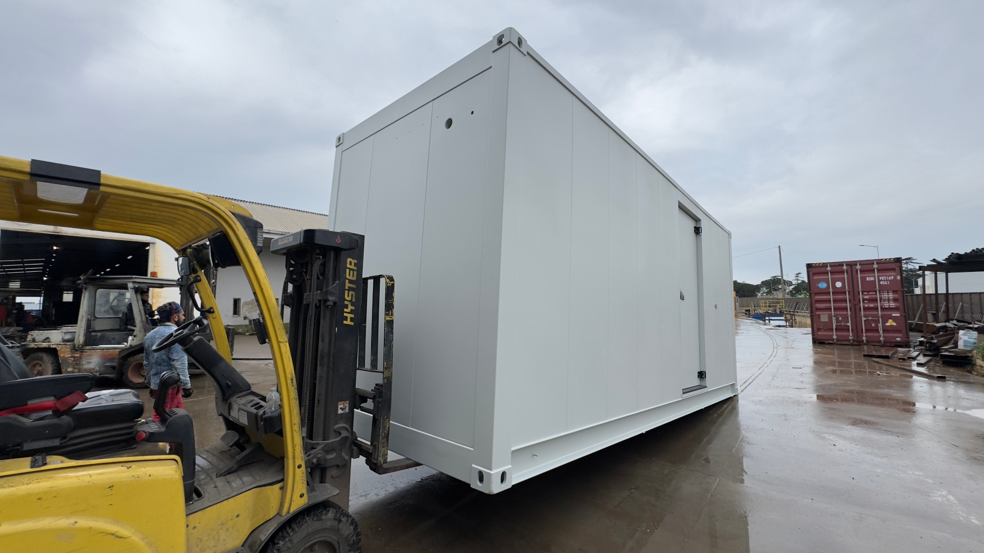 FlexEstack module being moved by forklift — showing the robust ISO corner castings and factory-finished white enclosure ready for transport.